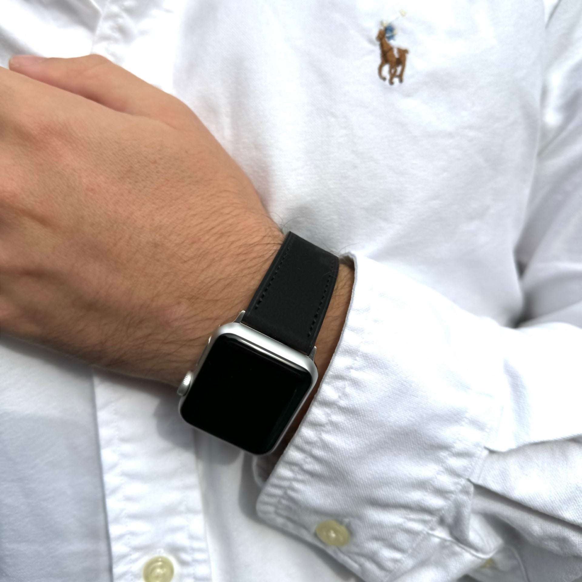 Schwarzes Nubukleder-Armband für Apple Watch am Handgelenk – Schrägansicht, eleganter Look mit schwarzer Hose und weißem Hemd im Hintergrund