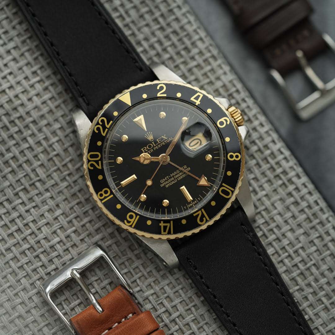 Schwarzes Barenia Glattleder 20mm Uhrenarmband an Rolex GMT Master Schwarz/Gold – Seitenansicht der Uhr mit strapazierfähigem, glänzendem schwarzen Alligatorlederarmband, ideal für sportliche und luxuriöse Zeitmesser