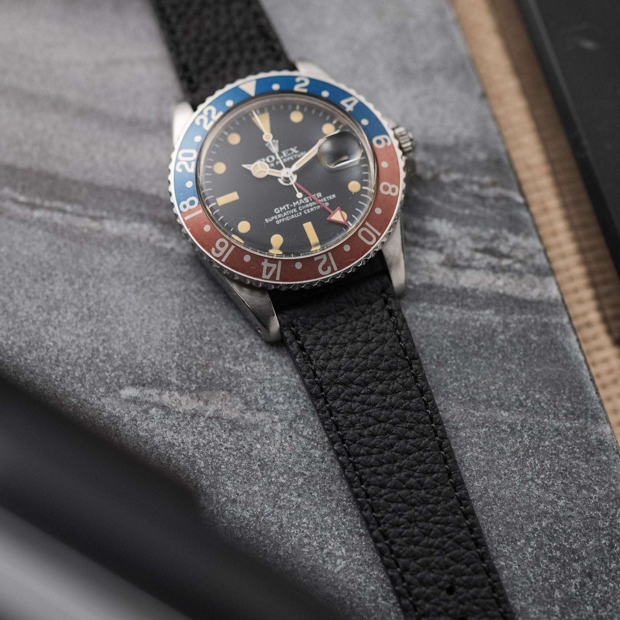 Schwarzes Deauville Uhrenarmband aus Togoleder an Rolex GMT Master II Pepsi auf Marmor