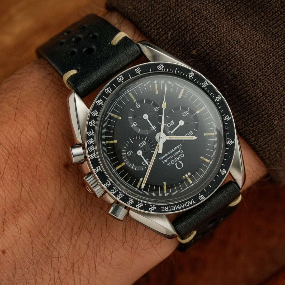 Schwarzes rustikales Racing Uhrenarmband an Omega Speedmaster – Seitenansicht der Omega Speedmaster Uhr mit strapazierfähigem, schwarzem Barenia Lederarmband, das für seine Langlebigkeit und sportliche Eleganz bekannt ist