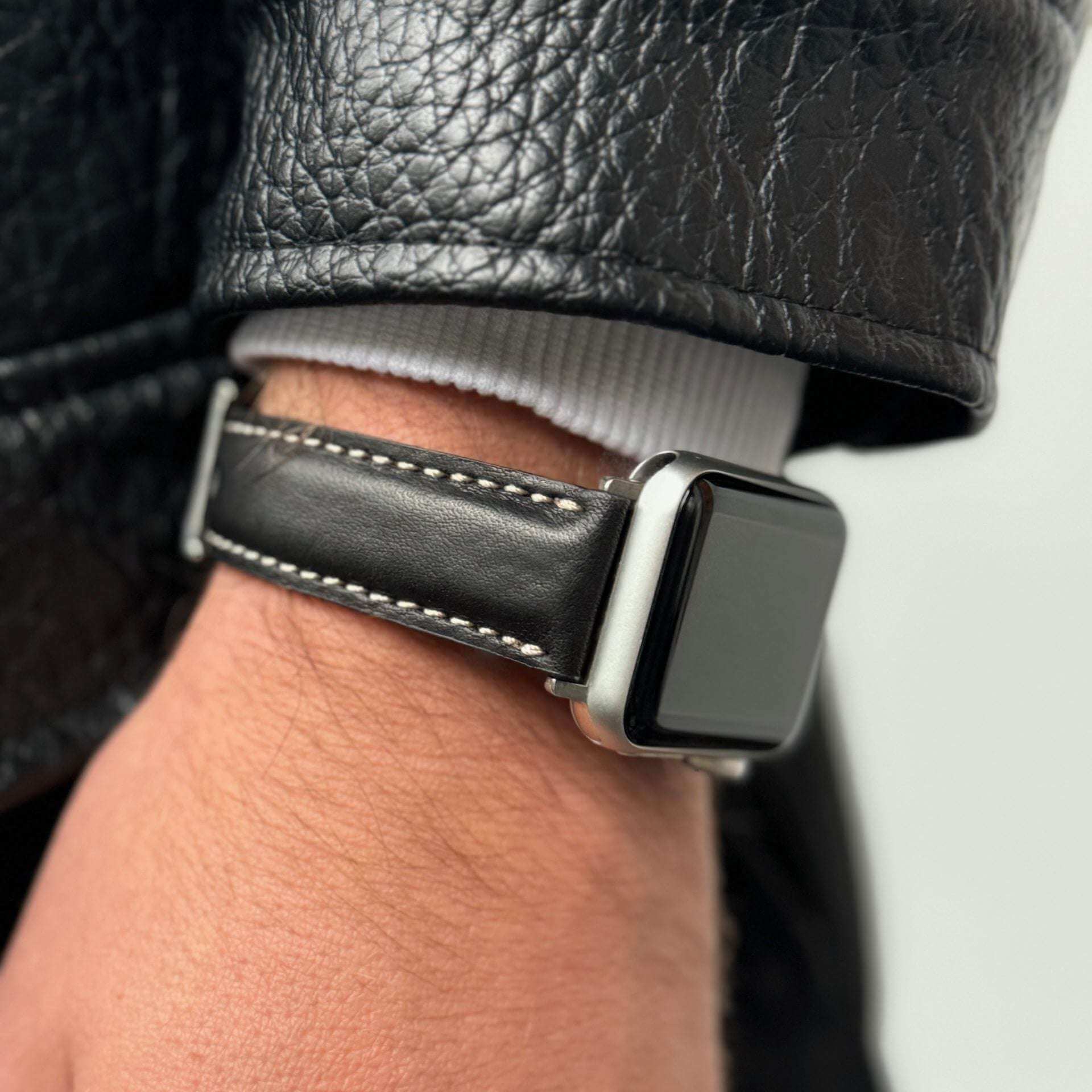 Apple Watch Ultra 2 Armband Leder in Schwarz getragen an einem Handgelenk, kombiniert mit einer Lederjacke.