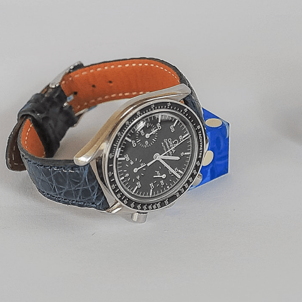 Shiny – Uhrenarmband aus glänzendem Kaimanleder an einer eleganten Uhr mit schwarzem Ziffernblatt.