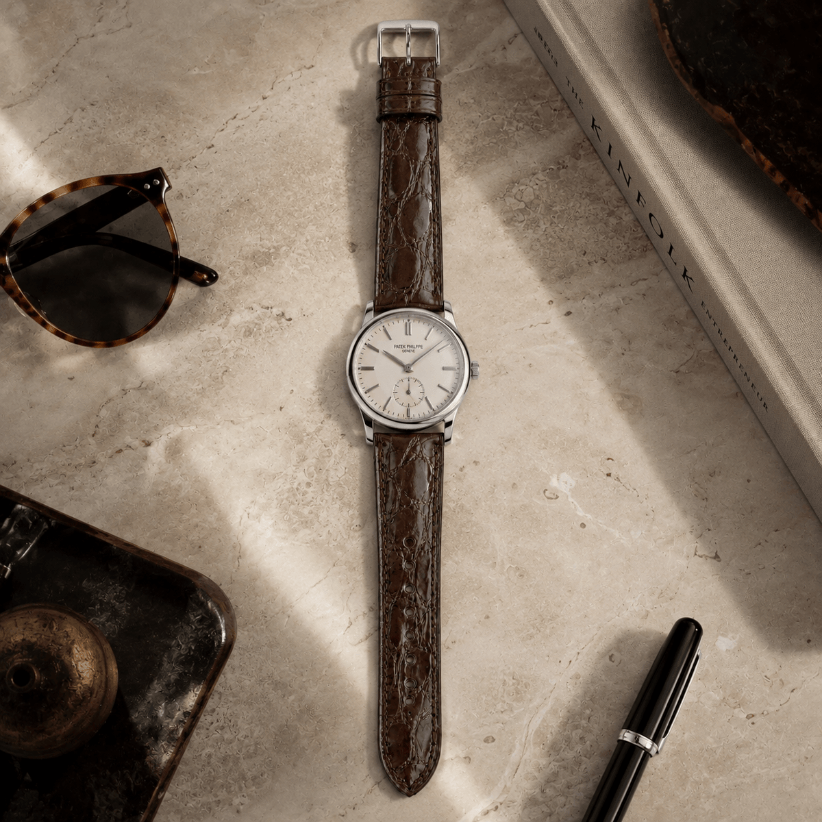 Shiny – Uhrenarmband aus glänzendem Kaimanleder an einer eleganten Uhr auf Marmoroberfläche.