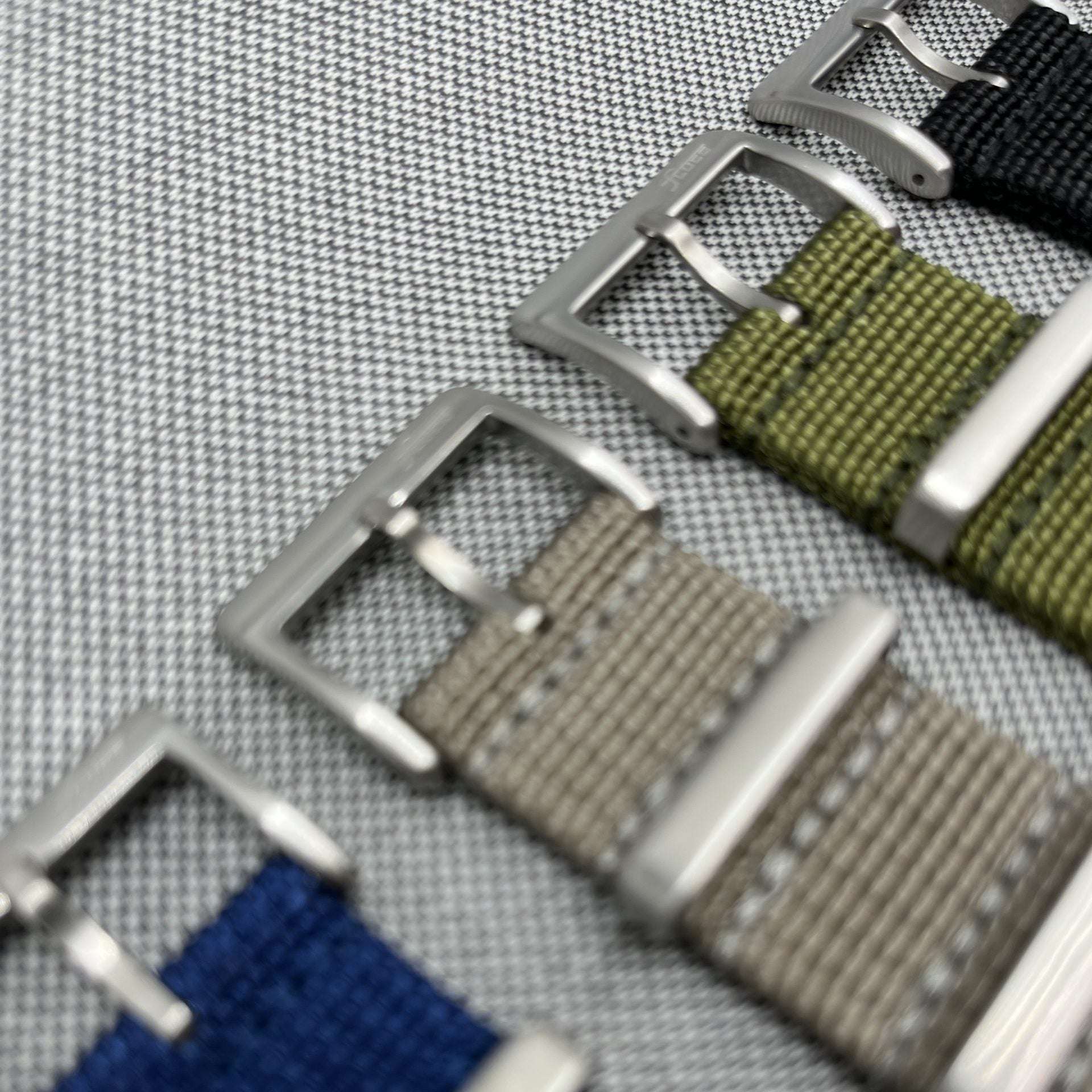 Vier verschiedene blaue NATO Bänder nebeneinander – Detailaufnahme von vier strapazierfähigen blauen NATO Bändern in unterschiedlichen Designs, einschließlich des blauen NATO Bands mit Fluco Logo