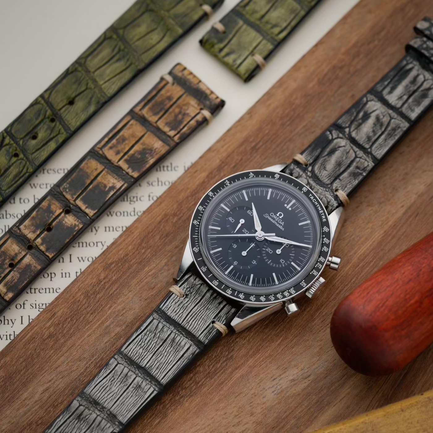 Eine stilvolle Aufnahme eines Vintage Alligator Uhrenarmbands, das an einer sportlichen Uhr befestigt ist, umgeben von anderen Uhrenbändern.